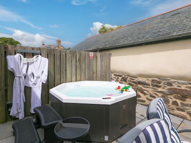An outdoor area with a hot tub and chairs at Carines Barns - Pen in Cubert