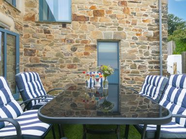 An outdoor dining area with a table and chairs at Carines Barns - Pen, Cubert