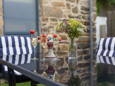 An outdoor seating area with champagne glasses and a cake at Carines Barns - Pen, Cubert