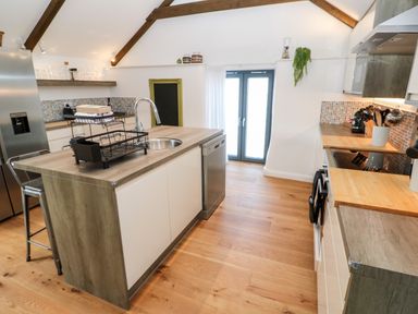 A kitchen with an island sink dishwasher and stainless steel refrigerator at Carines Barns - Par in Cubert
