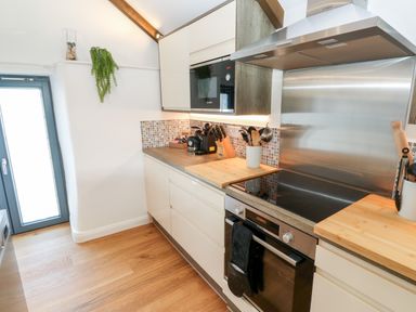 A kitchen with wooden countertops a stovetop an oven a microwave and kitchen utensils at Carines Barns - Par in Cubert