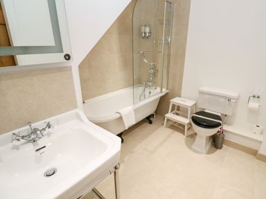 A bathroom with a sink toilet bathtub and a small step stool at Carines Barns - Par in Cubert