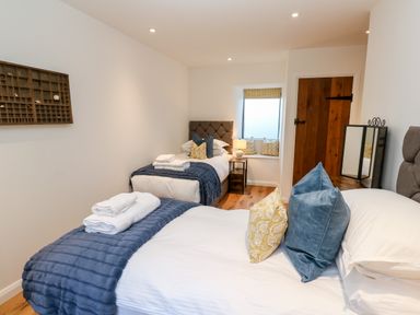 A bedroom with two single beds with pillows and folded towels next to a wooden door at Carines Barns - Par in Cubert