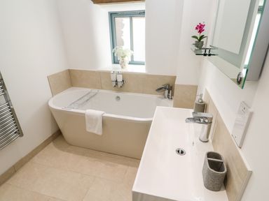 A bathroom with a bathtub towel and sink with faucet at Carines Barns - Par in Cubert