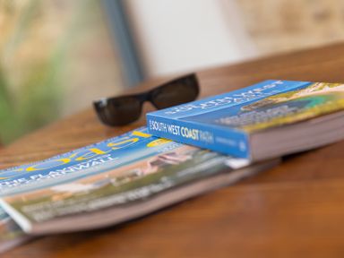 A guidebook and magazines on a wooden table at Carines Barns - Wesley Barn, Cubert