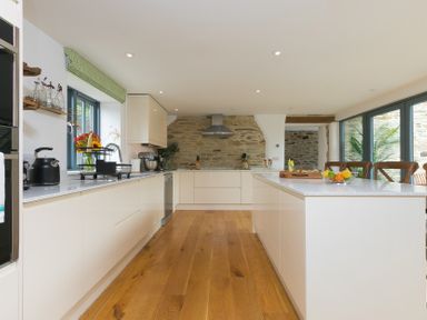 A kitchen with a stone wall and kitchen island at Carines Barns - Wesley Barn, Cubert