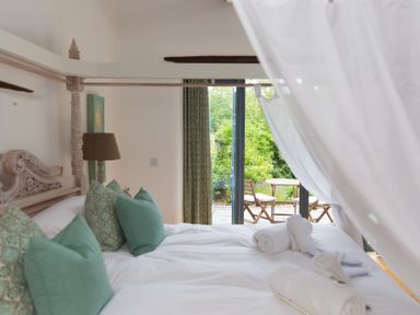 A bedroom with a bed and access to an outdoor patio area at Carines Barns - Wesley Barn, Cubert