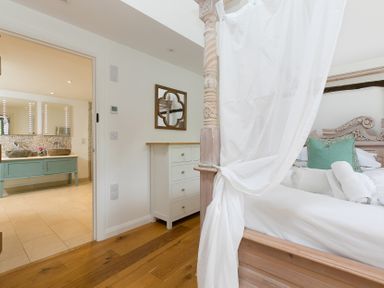 A bedroom with a bed and adjoining bathroom at Carines Barns - Wesley Barn in Cubert