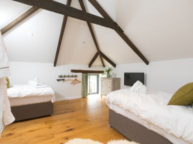 A bedroom with two beds and a television at Carines Barns - Wesley Barn, Cubert