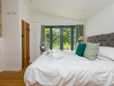 A bedroom with a bed and a garden view at Carines Barns - Wesley Barn, Cubert