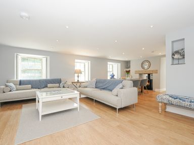 A living room with two sofas a white coffee table and a dining area at Cob Cottage near Rock