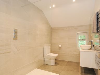 A bathroom with a toilet a sink with a countertop a window and a towel rack at Cob Cottage near Rock