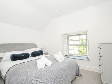 A bedroom with a bed with two rolled towels and two pillows next to a window at Cob Cottage near Rock