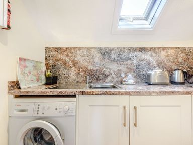 A kitchen counter with a sink a toaster a kettle and a washing machine below the counter at The Hayloft in St Florence