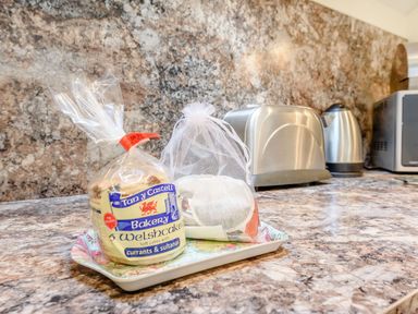 A kitchen counter with a pack of Welsh cakes on a tray and a kettle toaster and microwave in the background at The Hayloft in St Florence