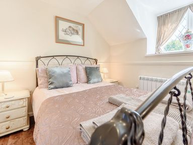 A bedroom with a double bed bedside tables lamps and a window with curtains at The Hayloft in St Florence