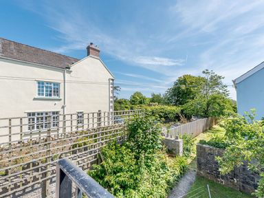 View of houses with garden fences trees and blue sky at The Hayloft in St Florence