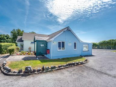 A blue and cream building with a small garden and parking lot at The Hayloft in St Florence