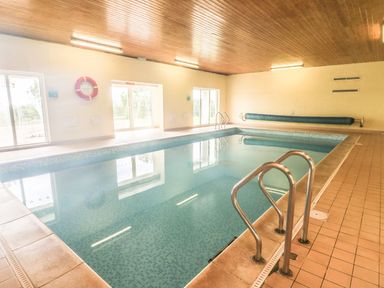 An indoor swimming pool with metal handrails and windows at The Hayloft in St Florence