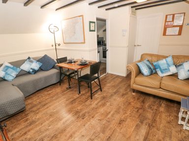 A living room with two sofas a small dining table with two chairs and wood flooring at The Hayloft in St Florence