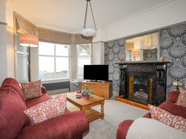 A living room with two red sofas a wooden coffee table and a fireplace at Llwyn Onn in Criccieth