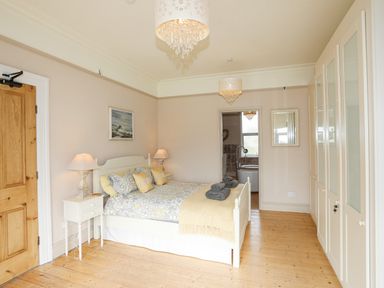 A bedroom with a double bed bedside tables lamps and a wardrobe at Llwyn Onn in Criccieth