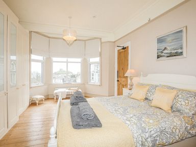 A bedroom with a bed linens curtains and windows showing outside view at Llwyn Onn in Criccieth