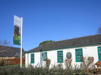 The Lloyd George Museum building with a banner and a sculpture bust outside in Criccieth
