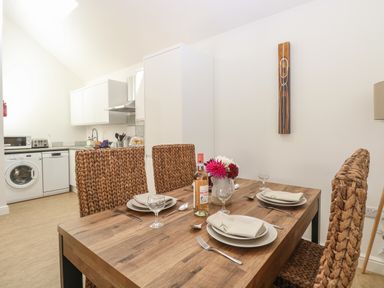 A dining table set for four with woven chairs in a kitchen area at Beck View Weston Longville near Lenwade