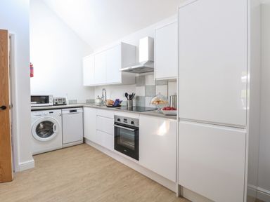 A kitchen with white cabinets appliances and wooden floor at Beck View in Weston Longville near Lenwade