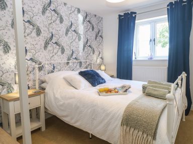 A bedroom with a double bed bedside tables and blue curtains at Beck View in Weston Longville near Lenwade