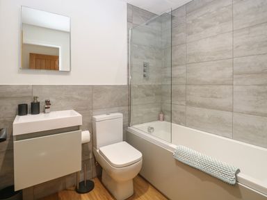 A bathroom with a sink cabinet toilet bathtub and a wall mirror at Beck View in Weston Longville near Lenwade