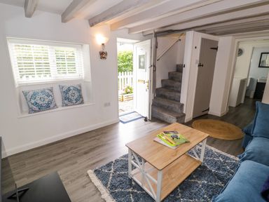 A living room with a sofa, table, and stairs at The Cottage in Ettington