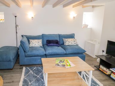 A living room with a blue sofa and coffee table at The Cottage in Ettington