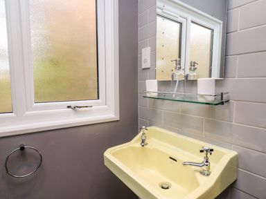 A bathroom with a yellow sink under a mirror and a window with frosted glass at Y Caban Glas in Rhydlewis near Brynhoffnant