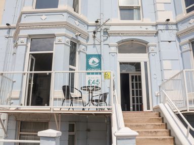 Entrance to a blue building with stairs leading to a door and a balcony with a table and two chairs at Beach Bridlington