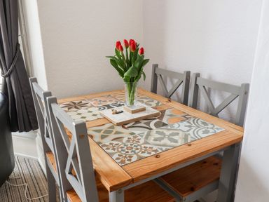 A dining table with patterned tiles and red tulips in a glass vase at Beach in Bridlington