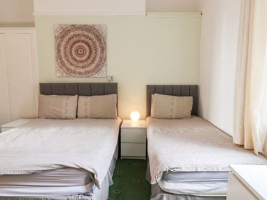 A bedroom with two single beds separated by a nightstand with a lamp and wall art above at Beach in Bridlington