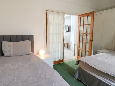A bedroom with two single beds a bedside table with a lamp and a wooden door leading to another room at Beach Bridlington