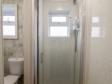 A bathroom with a toilet next to a shower cubicle with a window above the shower at Beach in Bridlington
