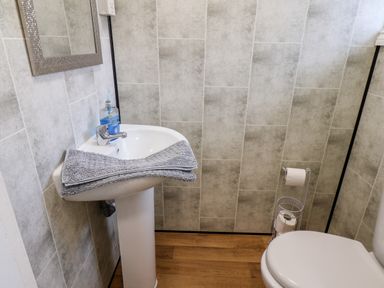 A bathroom with a pedestal sink a mirror a towel a soap dispenser a toilet and a toilet paper holder at Beach Bridlington