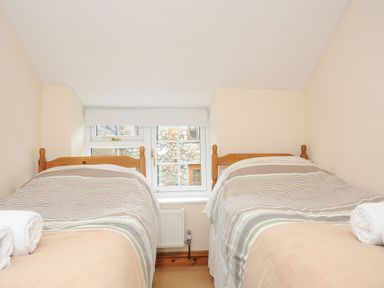 A small bedroom with two single beds and a window between at Henwood Barn in Henwood near Upton Cross