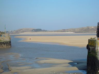 A river flowing into a sandy estuary with hills in the background at Henwood Barn in Henwood near Upton Cross