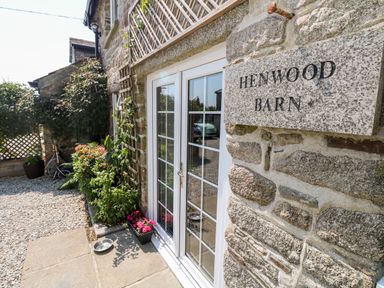 Exterior view of stone building with glass double doors plants and a sign reading Henwood Barn Henwood near Upton Cross