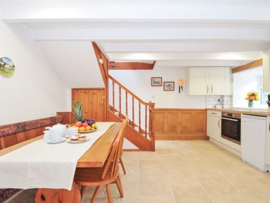 A kitchen with a dining area and staircase at Henwood Barn Henwood near Upton Cross