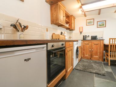 A kitchen with wooden cabinets white appliances and a dining table at Mole Cottage in Henwood near Upton Cross