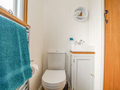 A small bathroom with a toilet sink cabinet and mirror at Gwithian Shepherds Hut in Angarrack near Hayle