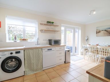 A kitchen with washing machine dishwasher microwave dining table and chairs at 23 Church Farm Lane in Halesworth