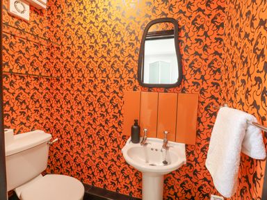 A bathroom with a toilet white sink mirror and towel on a rack at 23 Church Farm Lane in Halesworth
