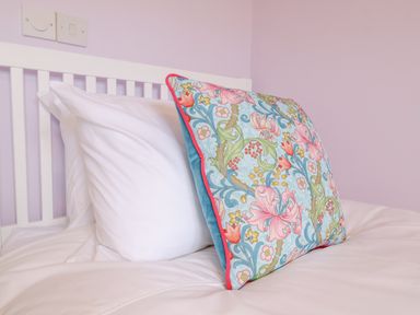 A bed with a white pillow and a decorative floral pillow at 23 Church Farm Lane in Halesworth